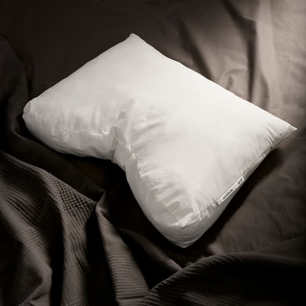 The fluffy IKEA SKOGSLÖK ergonomic pillow shown against dark grey bedlinen.