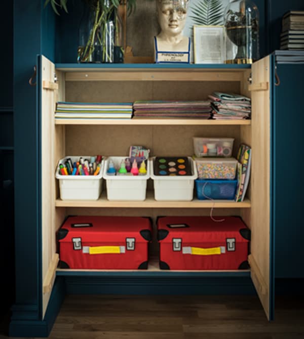 The inside of an cabinet is arranged to organise childrens’ art supplies.
