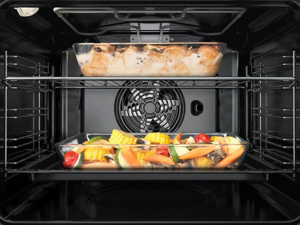 The interior of a modern oven with a tray of roasted vegetables