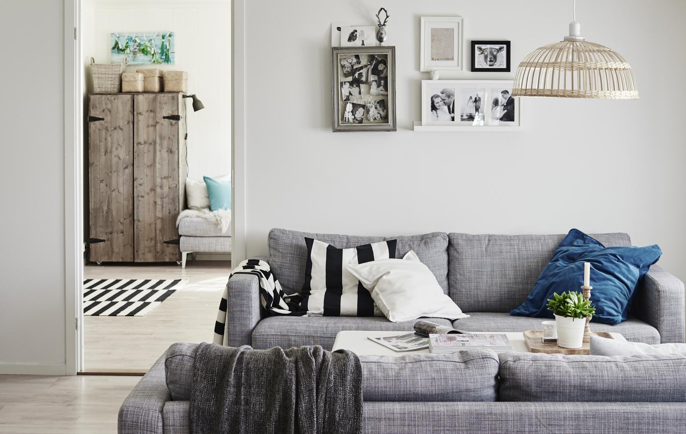 The layout of Gina’s living room, which includes two grey sofas facing each other, styled with blue accent cushion colours.