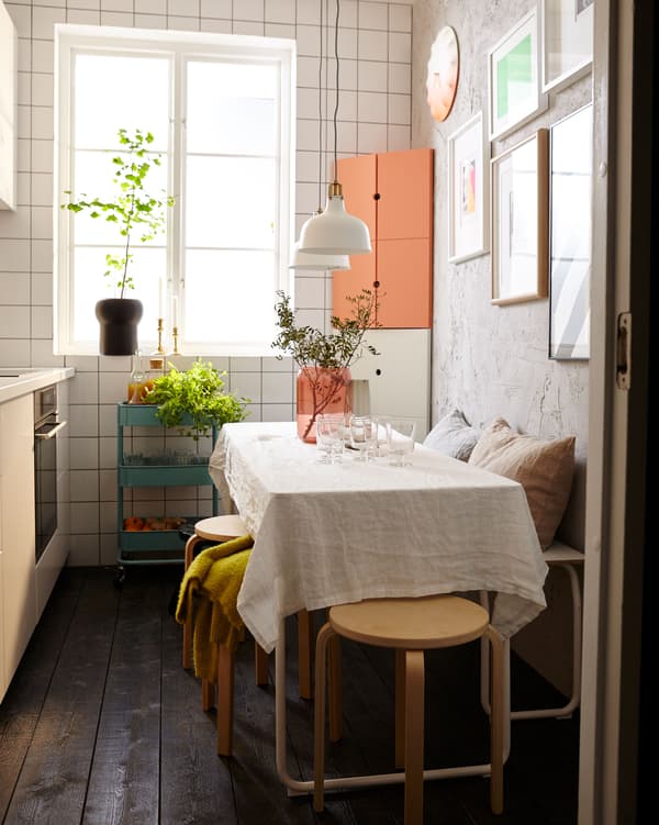 The same small kitchen is now outfitted for entertaining, with a set table, a bench, and stackable stools.