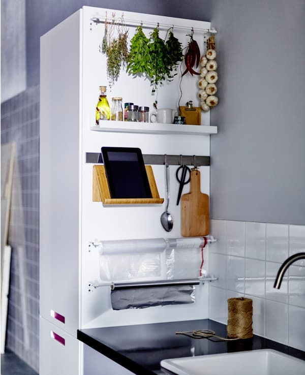 The side of a kitchen cabinet next to a work top stores and organises spices, scissors and a tablet stand.