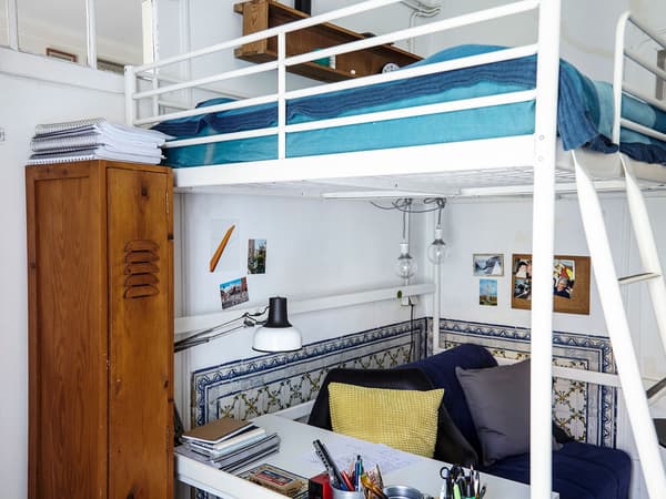 The sleep and study space of a student’s bedroom. A white loft bed with an area for work and relaxing below.