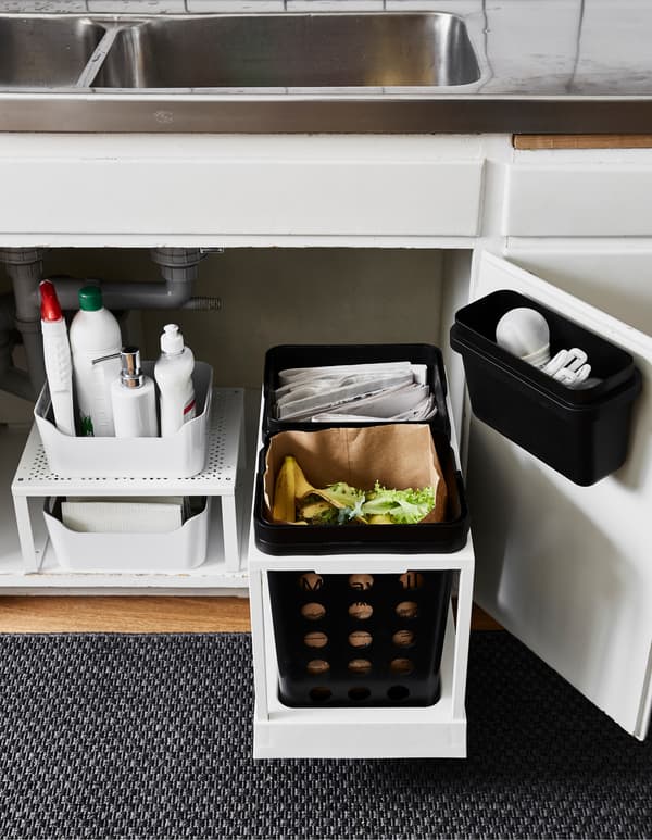 The space under the kitchen sink is updated with new storage that allows waste separation for recycling. On the right side two bins on a movable rail add functionality. To the left a shelf insert doubles storage space.