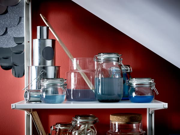 The top shelf of a large shelving unit under a sloped ceiling is stocked with crafting supplies.
