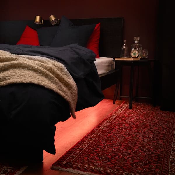 The underside of a bed is lit with a lighting strip.