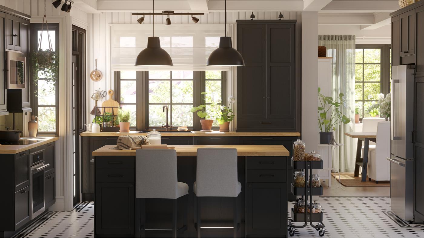 This is a big kitchen with black-stained LERHYTTAN fronts and a kitchen island with two black pendant lamps in the center.
