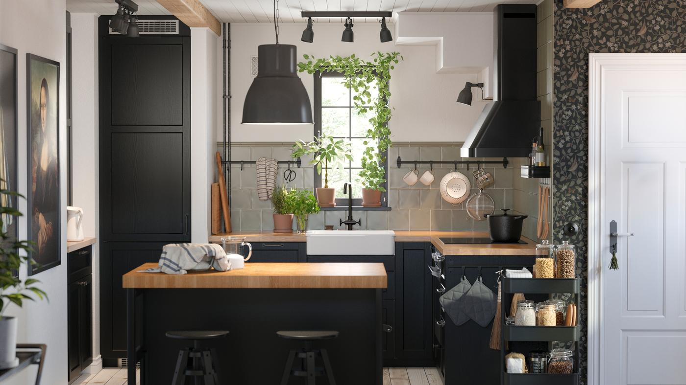 This is a small kitchen with black-stained LERHYTTAN fronts and a kitchen island with a black pendant lamp in the middle.