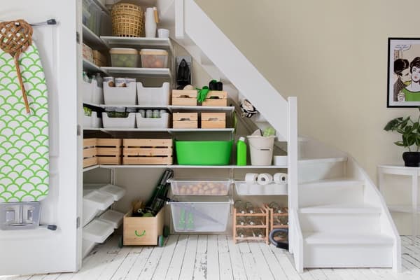 This thoughtfully organized space under the stairs offers a range of practical, IKEA-style storage solutions for various household items.