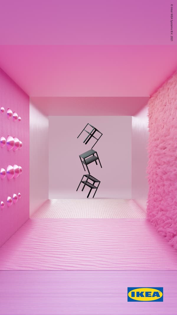 Three, black KNARREVIK bedside tables balance on one leg on top of each other in front of a ridged, pink wall.
