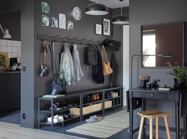Three black PINNIG bench shoe racks and three PINNIG racks with three hooks creating storage in a narrow hallway.
