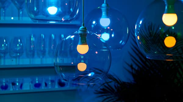 Three clear glass pendant light fixtures with lit lightbulbs inside.