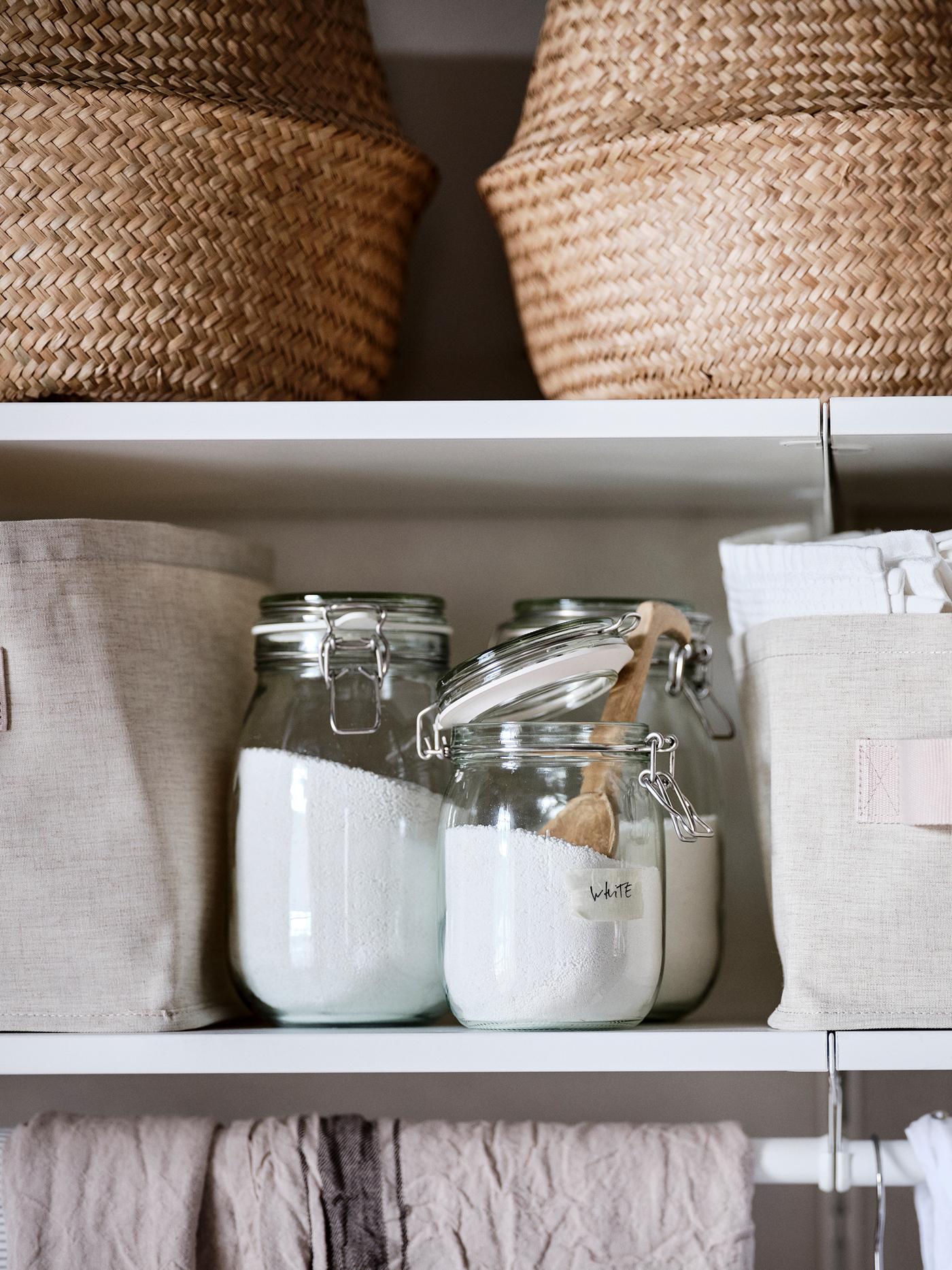 Three glass jars filled with washing powder, on a white BOAXEL shelf.