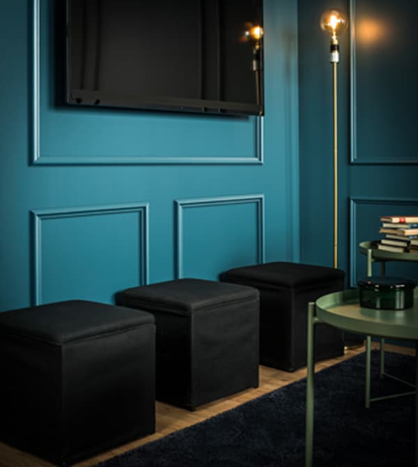 Three ottomans sit beneath a wall-mounted TV.