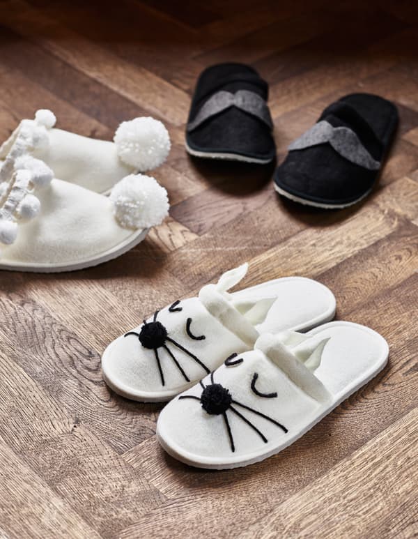 Three pairs of customised slippers sit on the floor.
