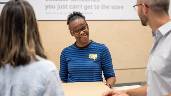 Three people are having a conversation, with one person facing the camera and the other two facing away.