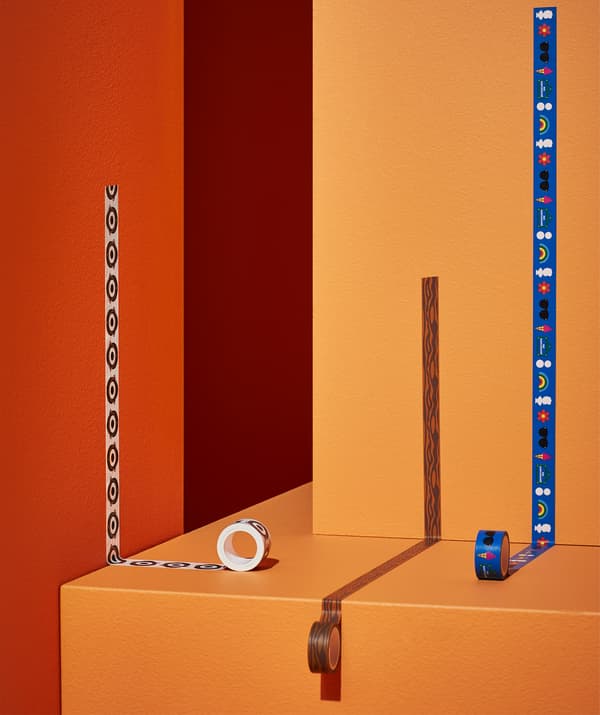 Three rolls of patterned washi tape rolled out on orange and red walls and steps.