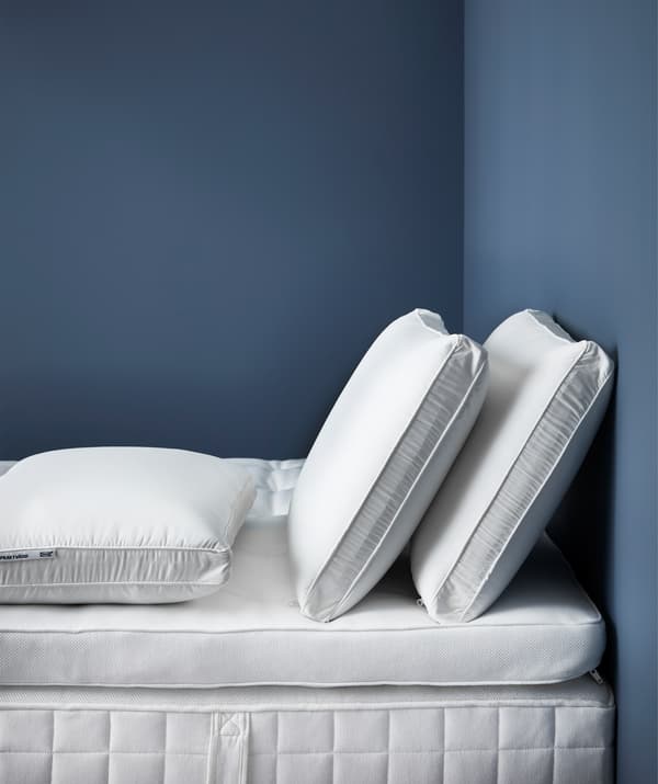 Three side sleeping ergonomic pillows on a mattress base with mattress topper.