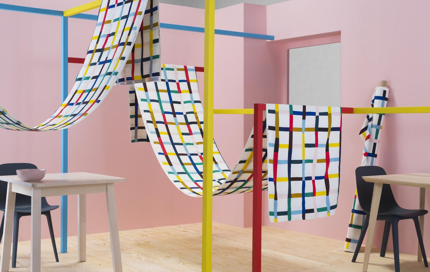 Tissu à motifs multicolores, enroulés autour de structures colorées dans une chambre à coucher rose.