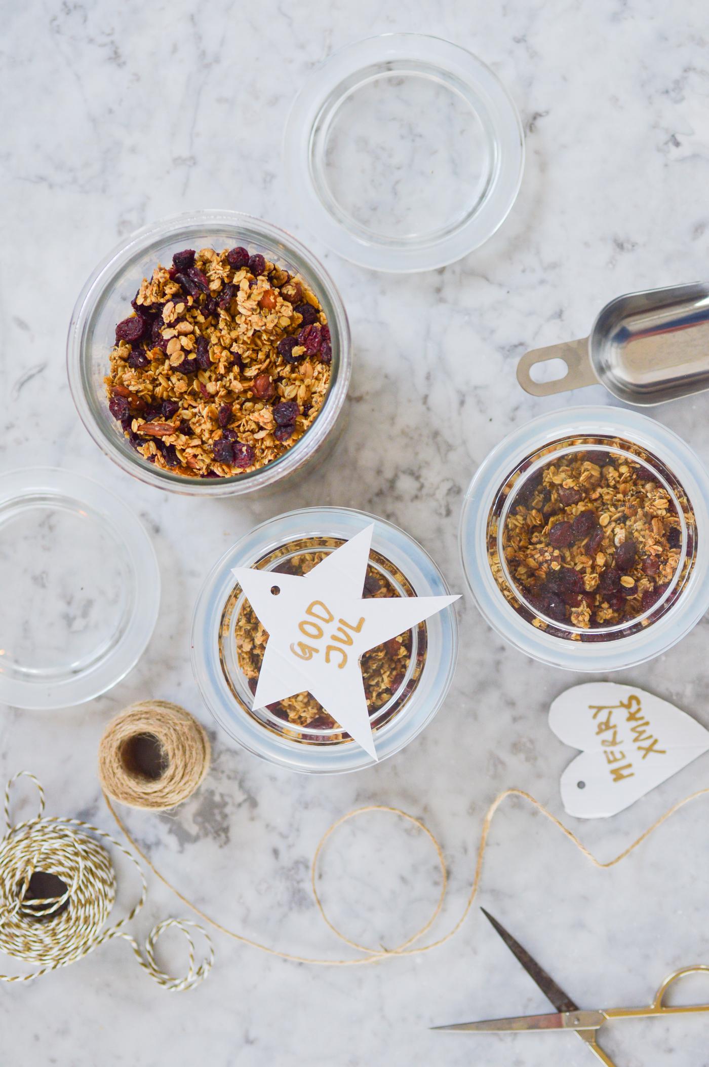 Top view of jars filled with muesli on a marble surface, surrounded by string, scissors and gift tags. This creates a festive atmosphere reminiscent of homemade gifts.