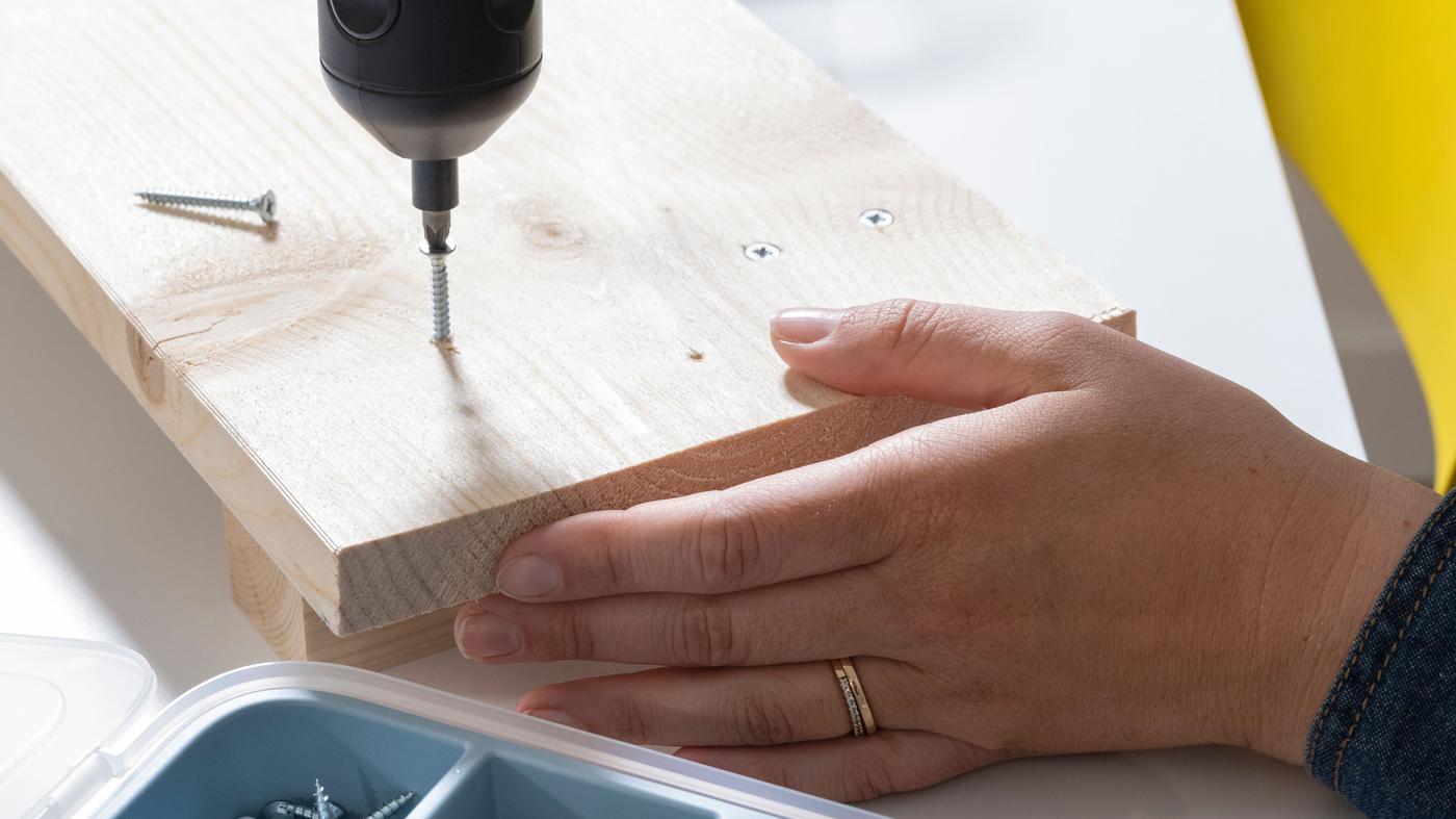 Tournevis électrique vissant une vis dans un morceau de bois.