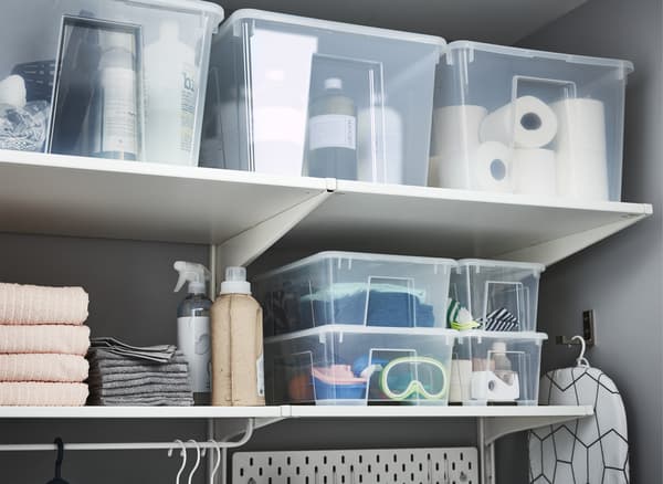 Transparent plastic boxes filled with laundry-related items and stacked on shelves.