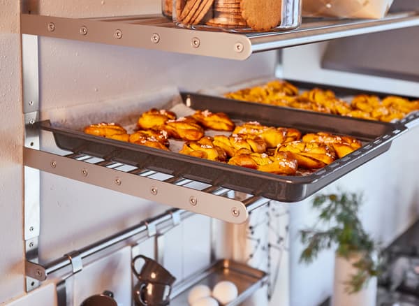 Trays of buns straight from the oven sit on metal shelving above the kitchen counter.