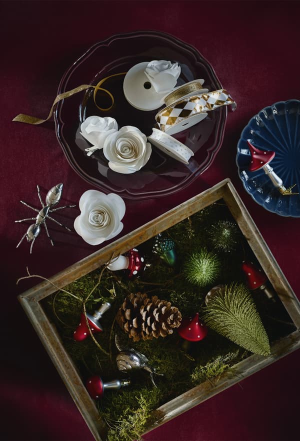Tree decorations and ribbon in bowls and boxes on a table.