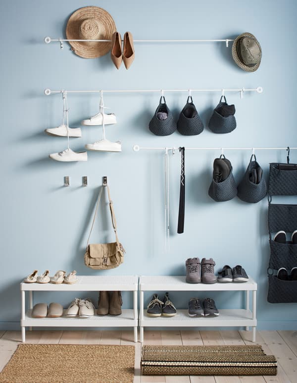 Tringles fixées au mur et auxquelles sont accrochés des paniers crochetés, le tout, placé au-dessus de deux range-chaussures.