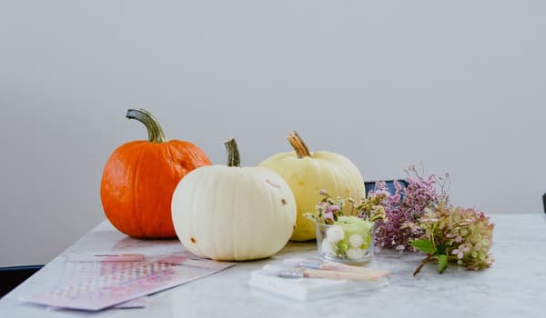Trois citrouilles, des fleurs séchées et des autocollants sur une table