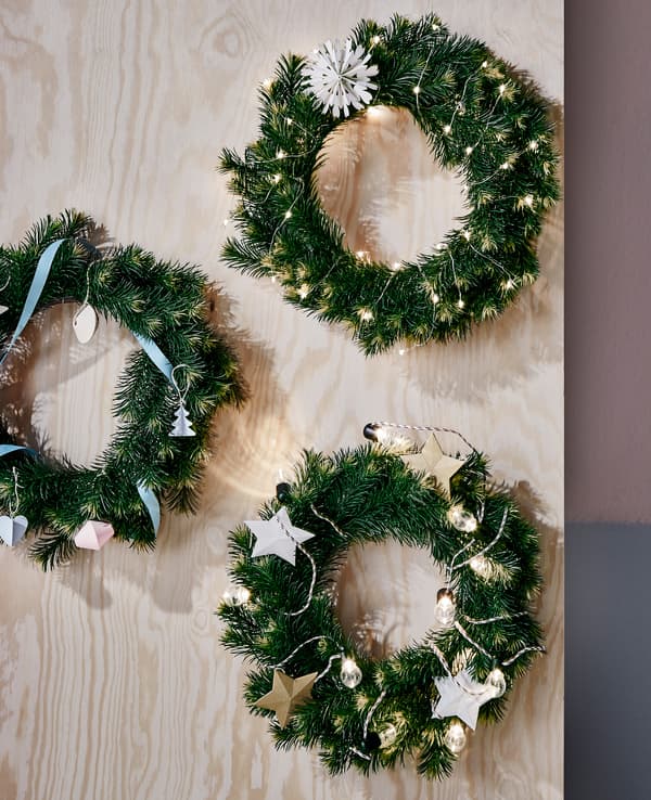 Trois guirlandes de Noël toutes simples accrochées à une planche en bois.