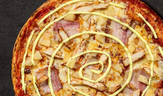 Тропическая пицца с куриным филе, беконом, ананасами и спиралью из соуса карри.