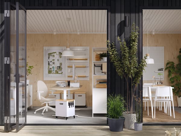TROTTEN desks and other office furniture in a sleek one-storey building with open French doors and a wooden deck outside.