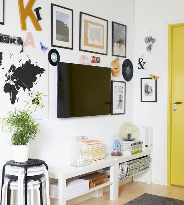 TV fixée au mur et entourée de reproductions sous cadre, pour créer un effet galerie.
