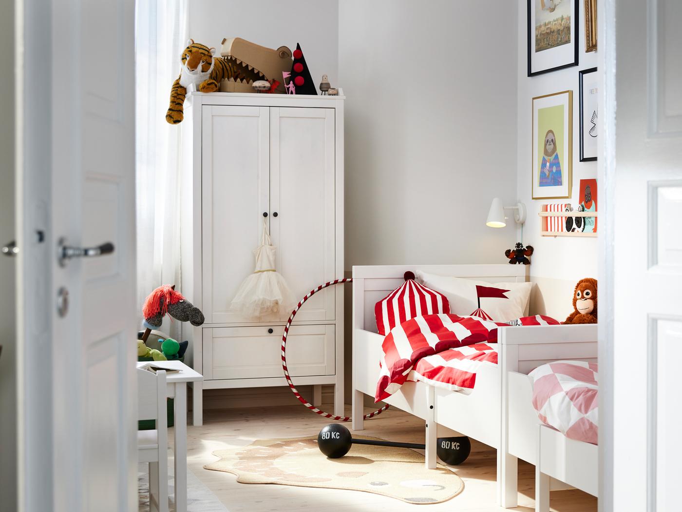 Twee SUNDVIK uitschuifbare bedden staan tegenover elkaar tegen een muur bij een witte SUNDVIK kledingkast in een slaapkamer.