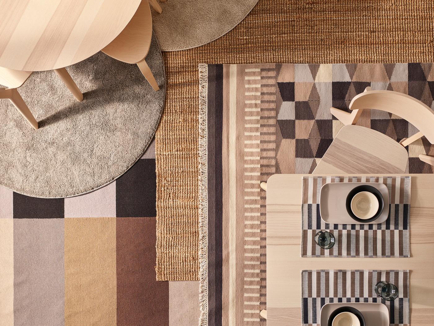 Two ash veneer LISABO tables and chairs stand on a floor with different rugs, including a LOHALS rug and some patterned ones.