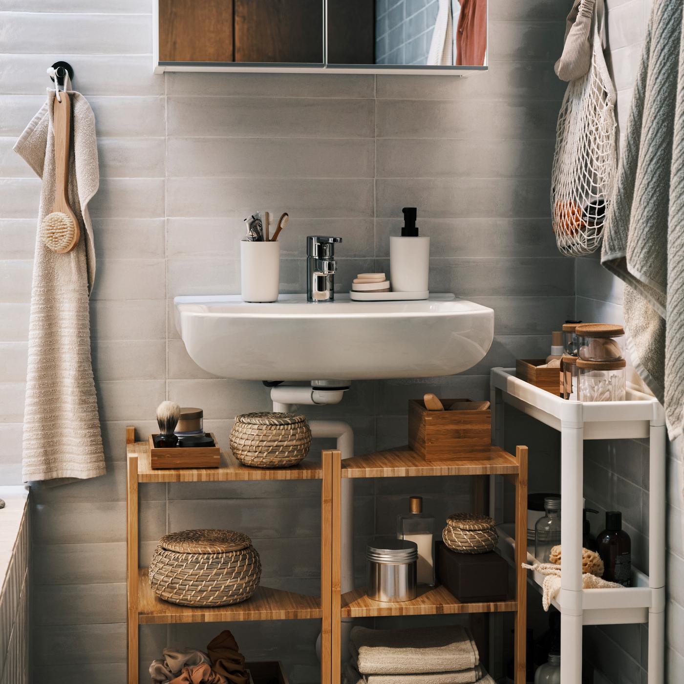 Two bamboo wash-basin/corner shelves under a wash-basin with a white mirror cabinet over it, plus a trolley and a hand towel.