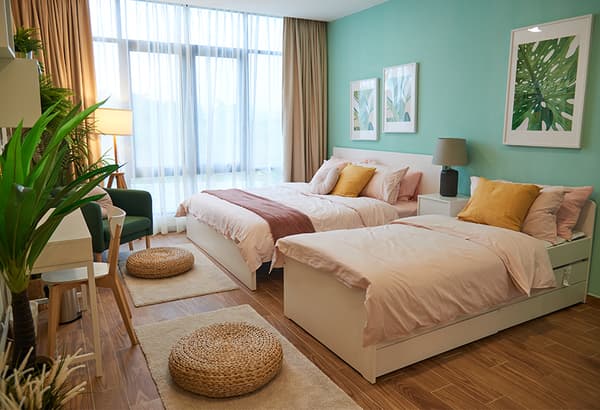 Two beds are placed against a turqoise wall .