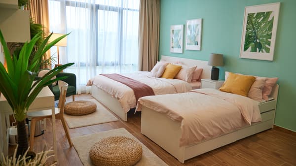 Two beds are placed against a turqoise wall.