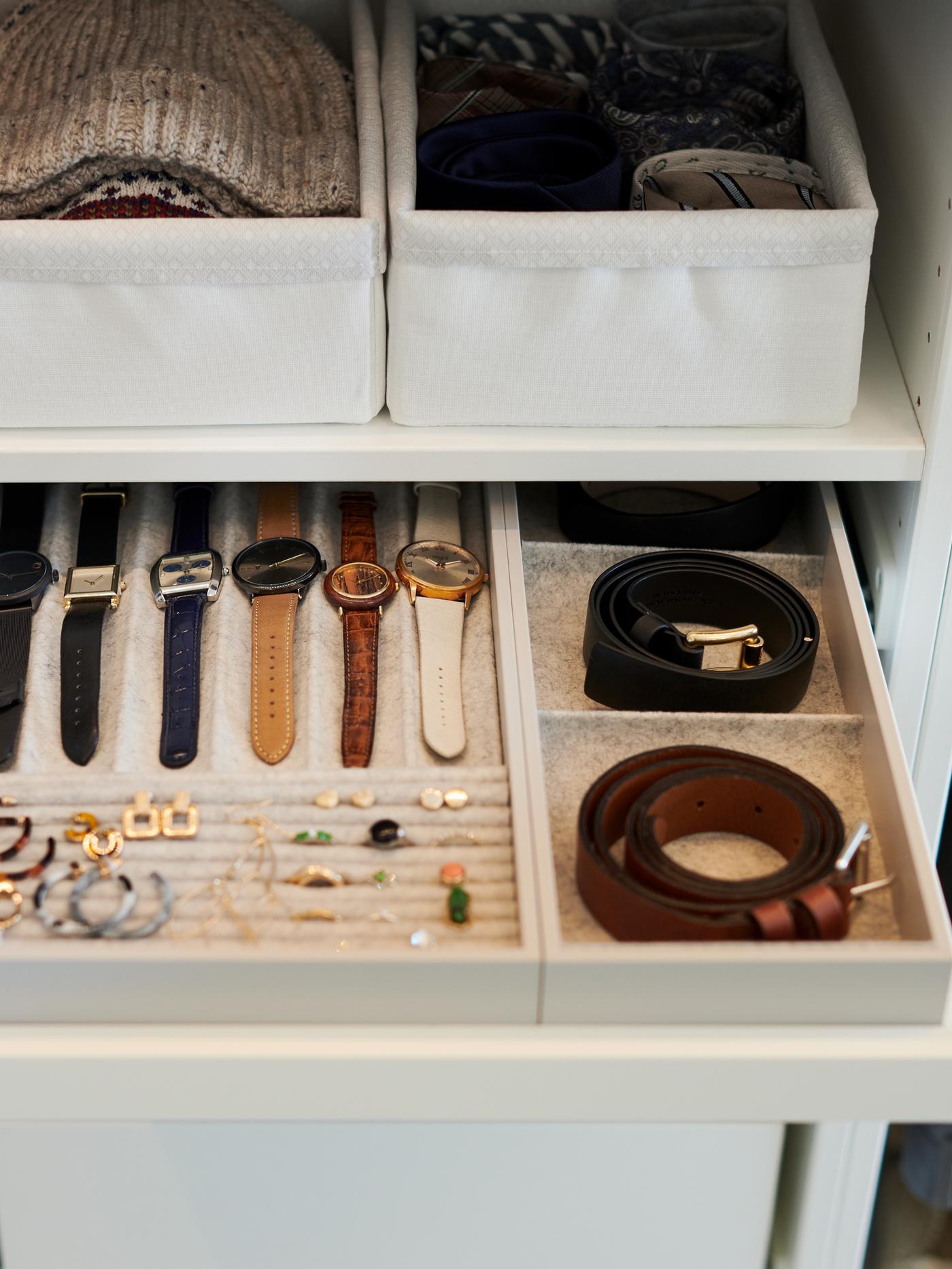 Two belts, six wristwatches and several pairs of earrings in a white KOMPLEMENT pull-out tray with insert.