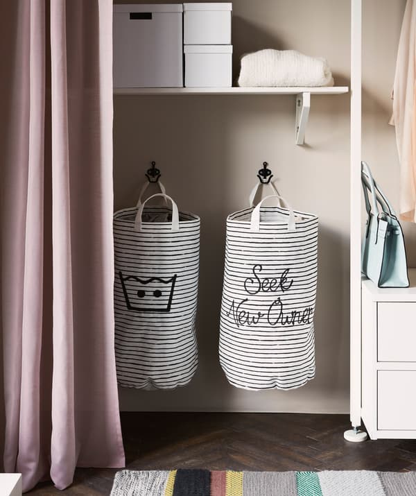Two black and white striped laundry bags hanging inside an open storage solution.