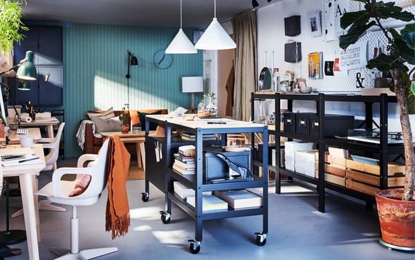Two BROR black/wood trolleys with storage on castors, two white pendant lamps and a long black shelving unit.