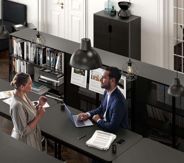 Two business people discuss over a laptop at an IKEA business layout for the IKEA for Business payment card​