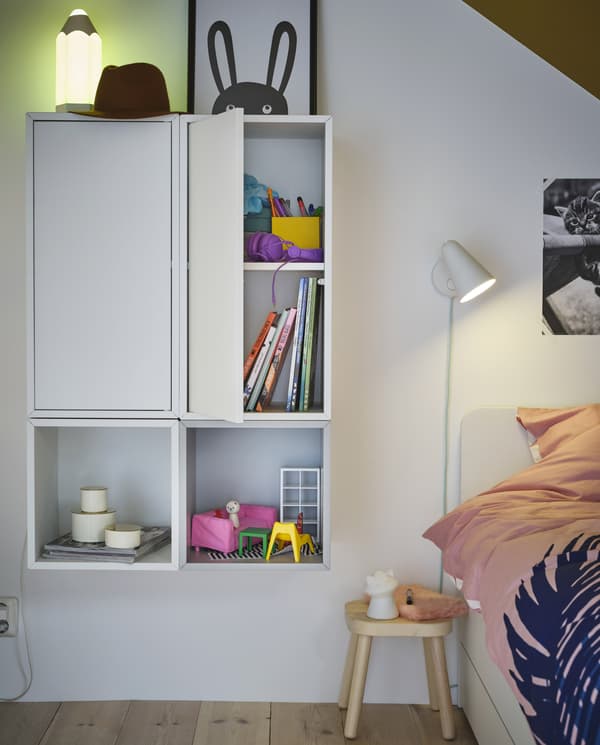 Two cabinets and two open units are wall-mounted and create a uniform storage solution. Books and toys are stored here.