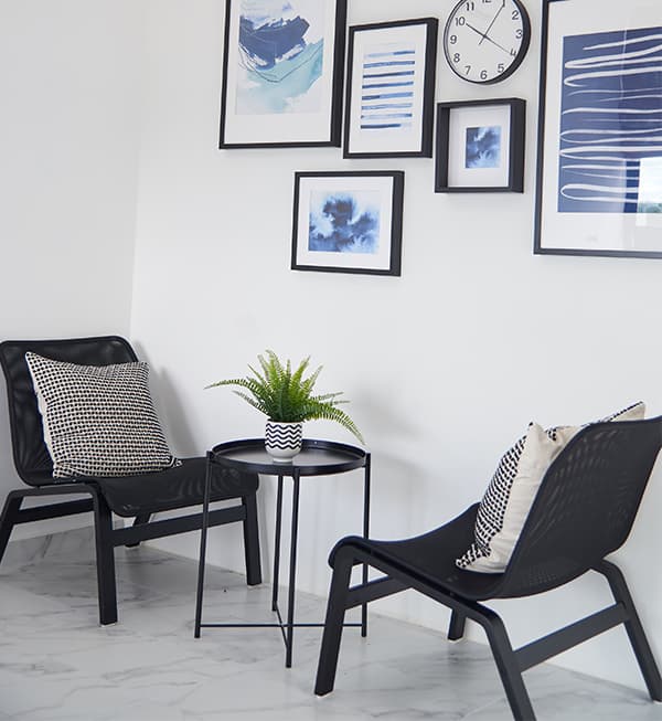 Two chairs facing each other with small black side table in the middle with a small potted plant.