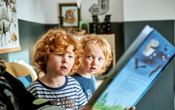 Two children being read to from a blue story book.