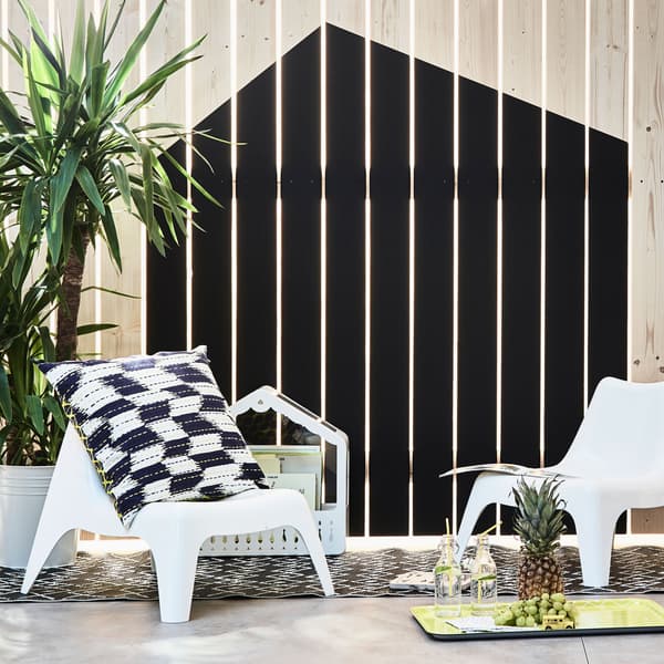 Two children’s easy chairs arranged by a fence that’s painted to look like a house 