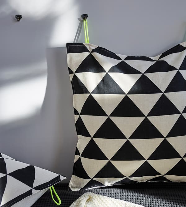 Two cushions with a black and white irregular print hung on a wall.