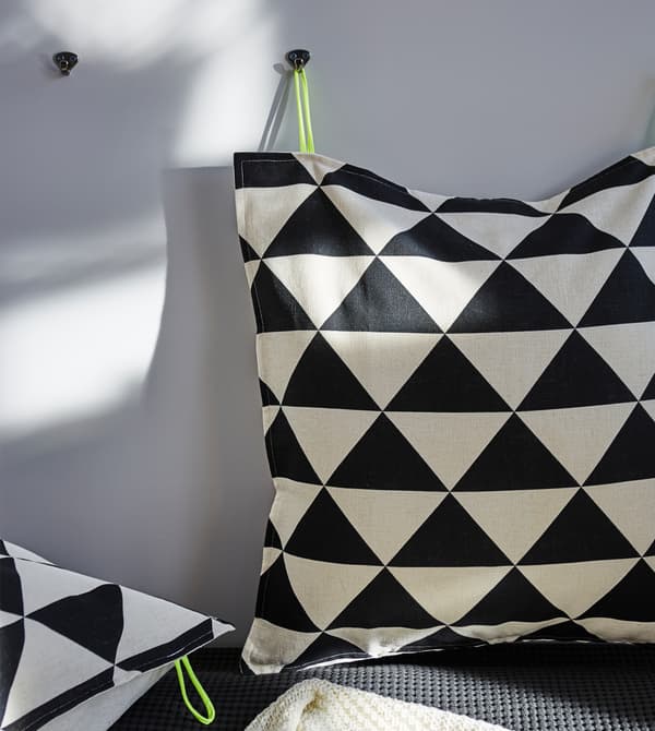 Two cushions with a black and white irregular print on the wall.