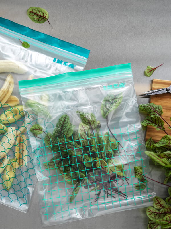 Two different-size ISTAD resealable plastic bags, filled with fruits and vegetables.